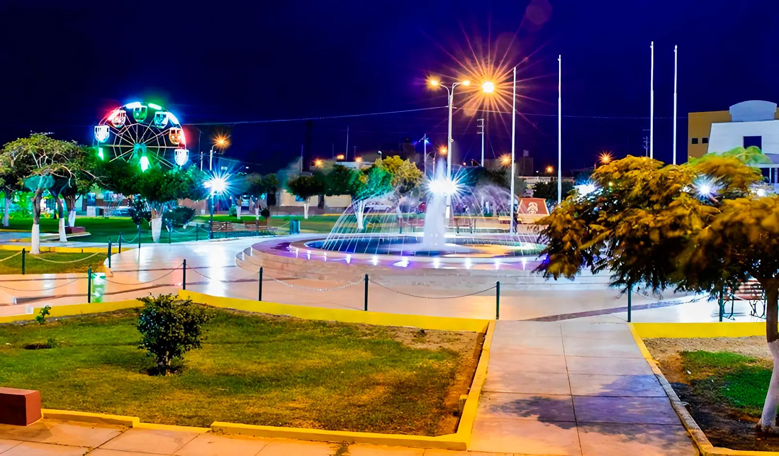 Plaza de Pueblo Nuevo de noche con pileta ornamental y rueda de la fortuna.