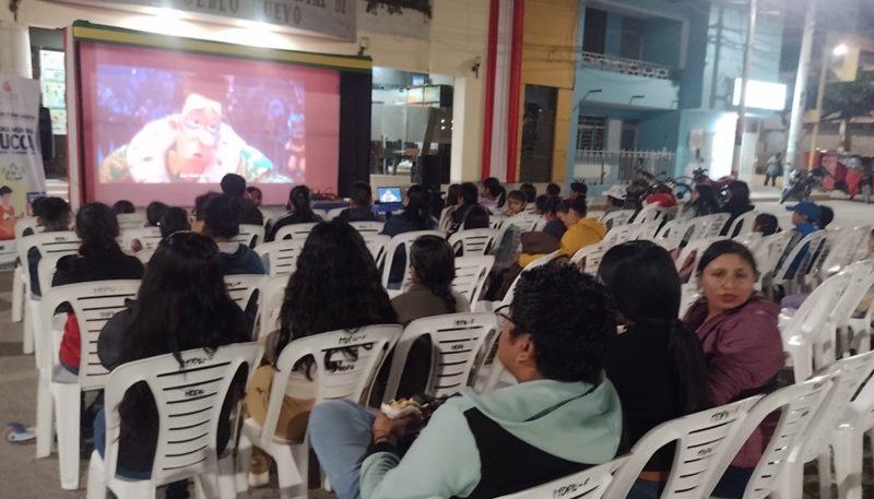 Vecinos reunidos en una función de cine comunitario al aire libre.